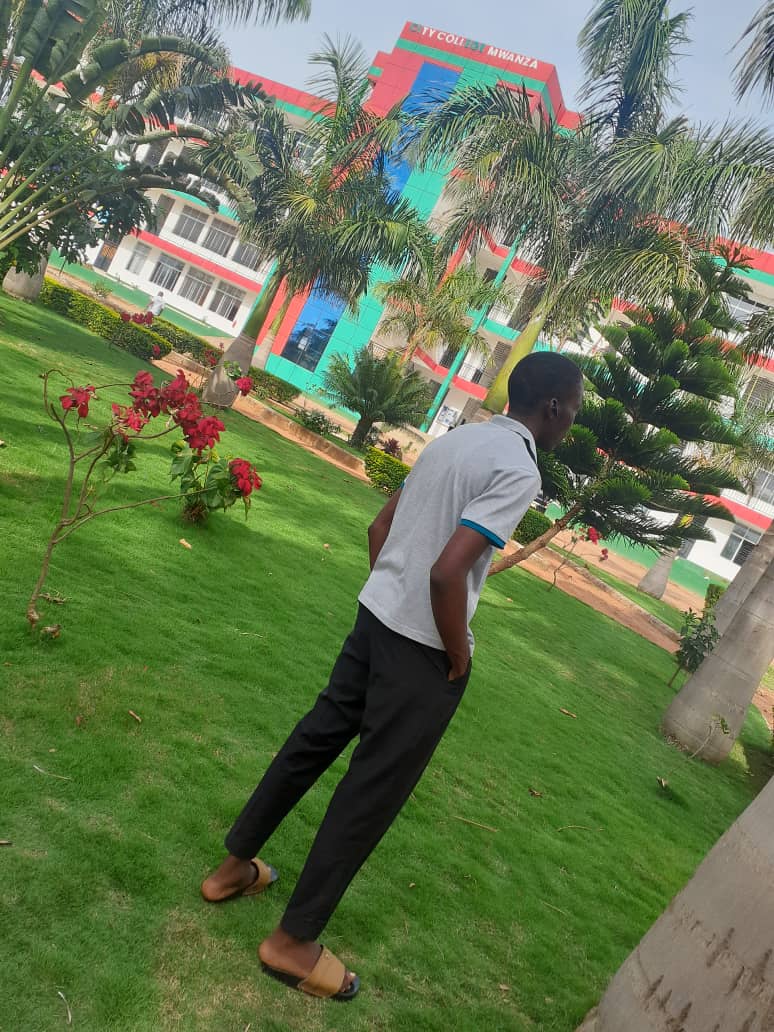 Junior standing in front of City College Mwanza.