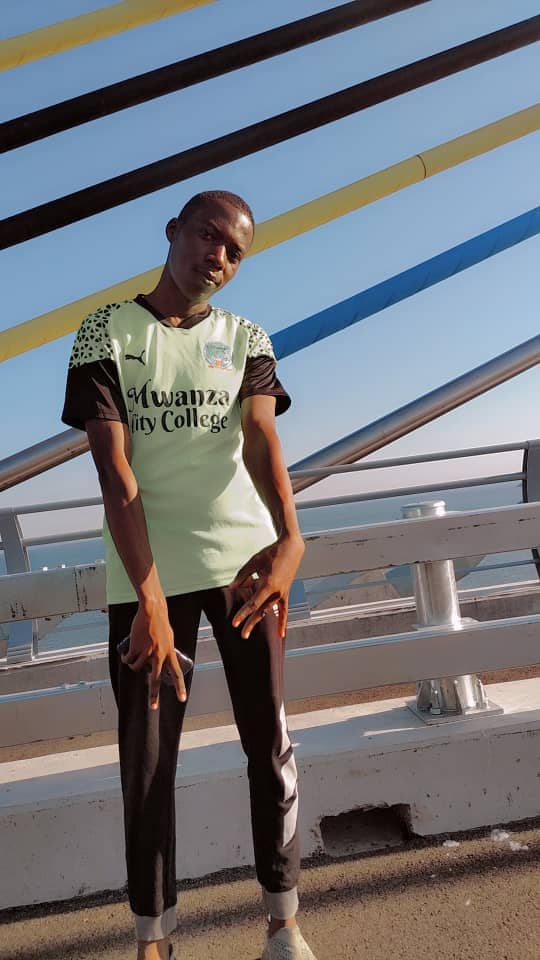 Junior wearing a Mwanza City College jersey on a bridge.
