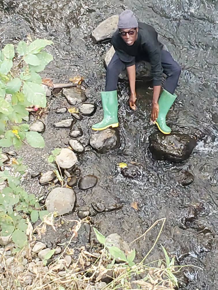 Junior standing in a stream wearing green boots.